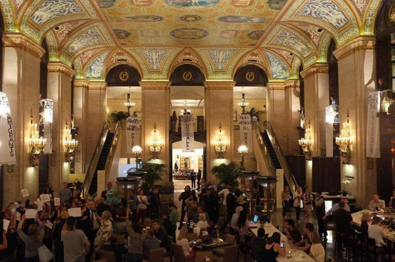 Protestors drop three banners inside the Palmer House Hilton