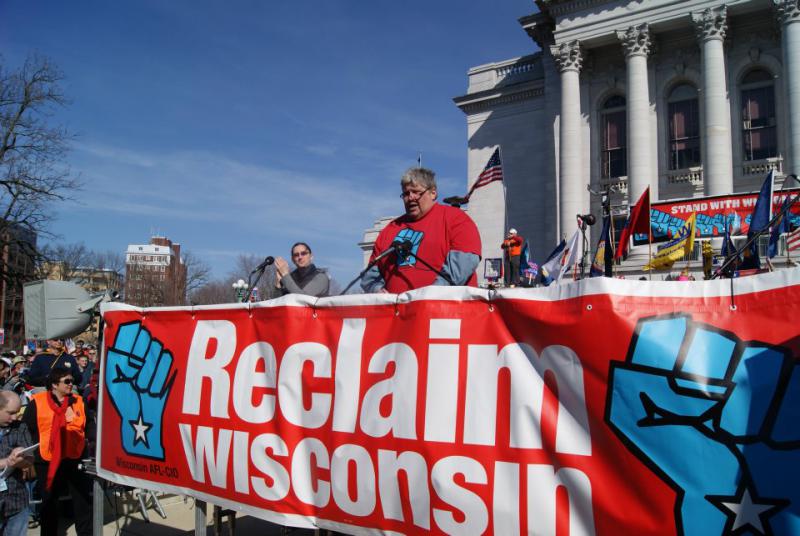 Phil Neuenfeldt speaking behind "Reclaim Wisconsin" banner
