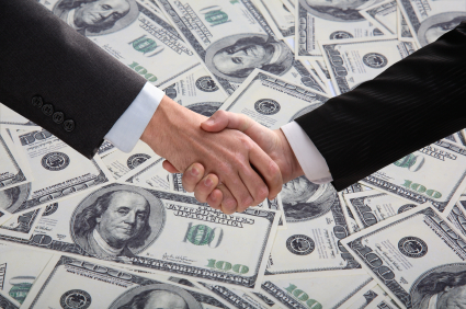 Businessmen shake hands over money