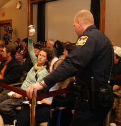 Protestor holding up jar of water in hearing on mining bill.