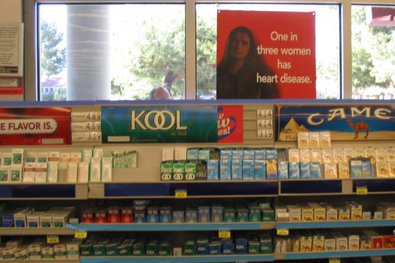 Rite Aid cigarette display with "Go Red for Women" poster above.