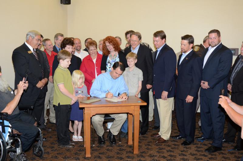 WI Gov. Scott Walker signs concealed carry legislation with the NRA's Wayne LaPierre looking on (via Blue Cheddar blog)